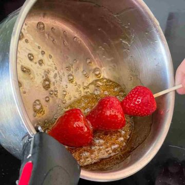 dip strawberry skewer into tanghulu syrup