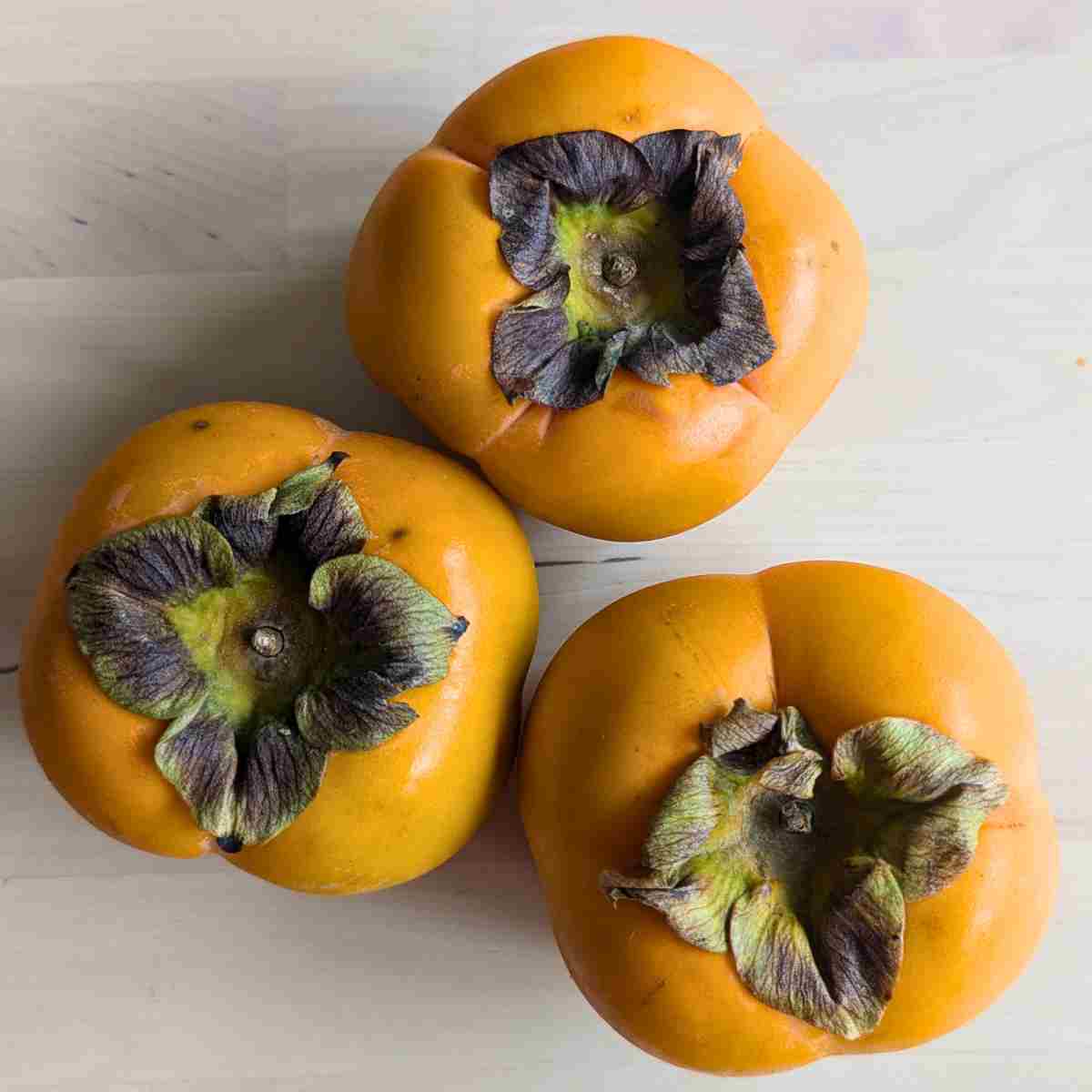 whole persimmon sharon fruit on table