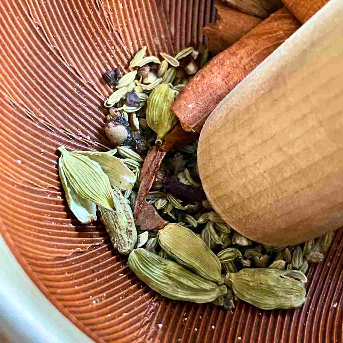 Crush chai spices in pestle and mortar
